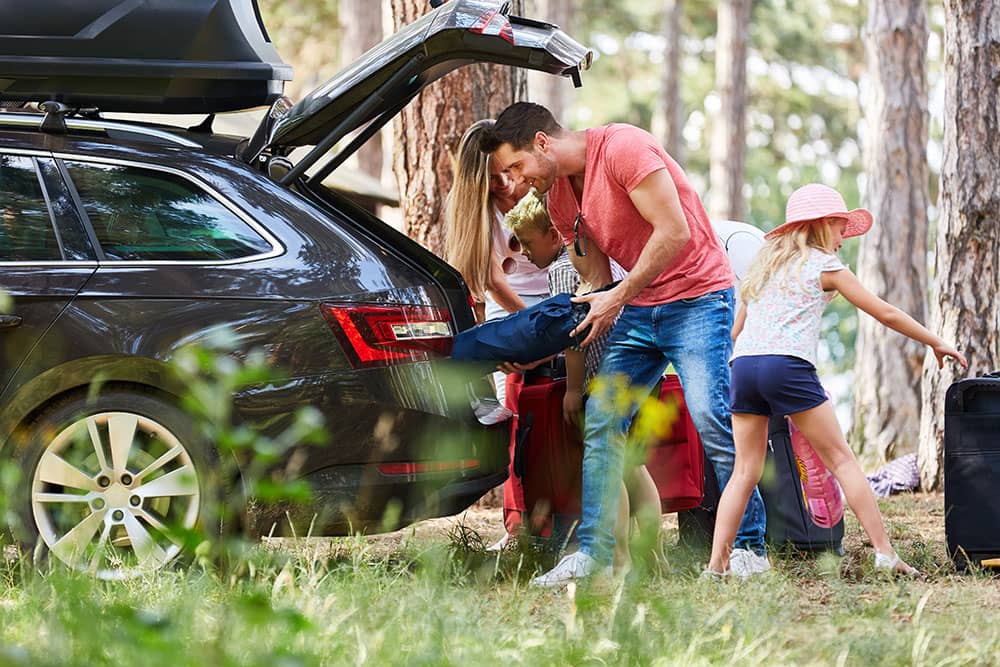 family on camping holiday packing car