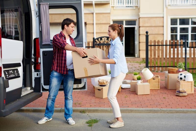 Couple unloading boxes from van.